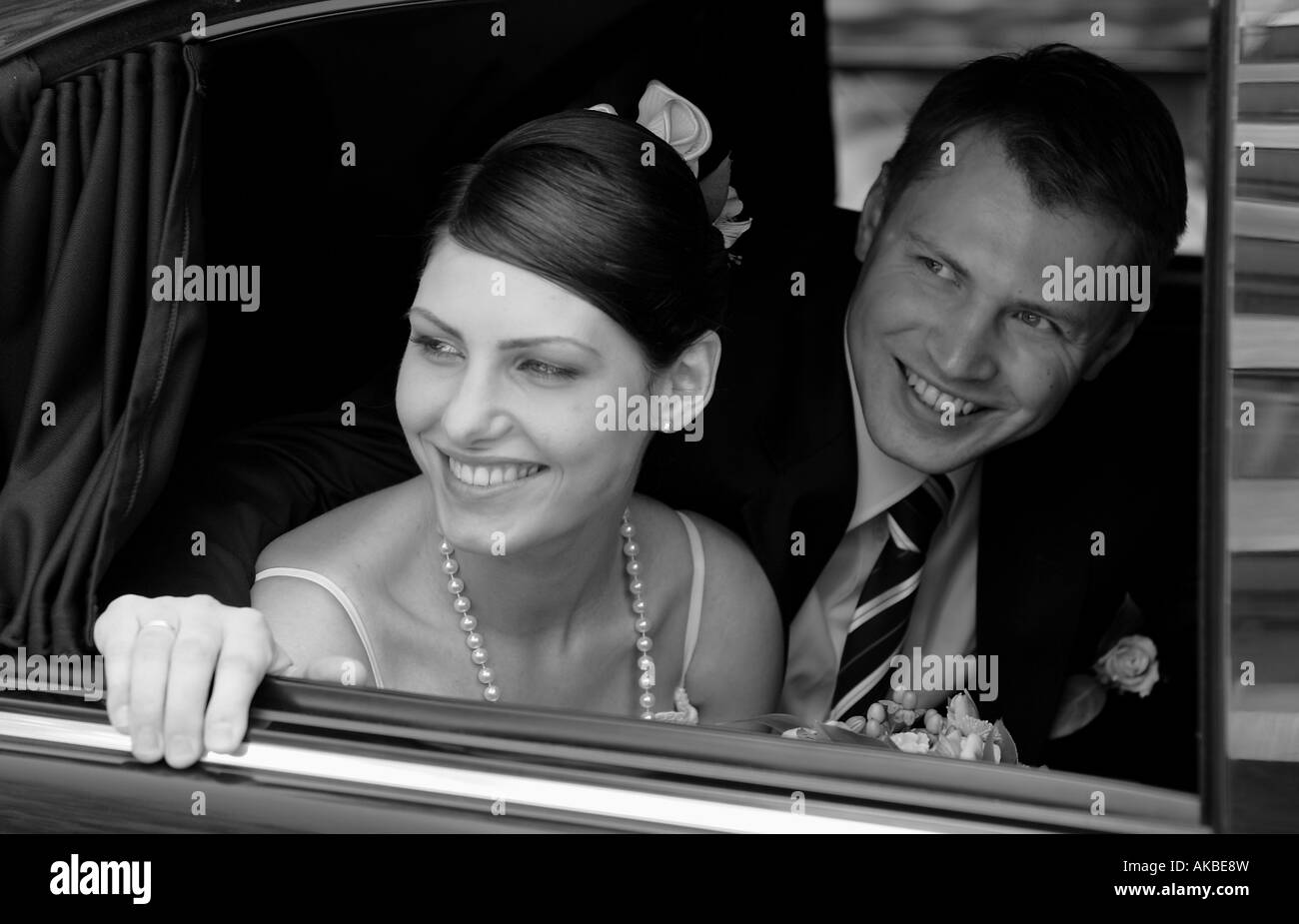Bride and groom in wedding car limousine. They are smiling out of the window. Stock Photo