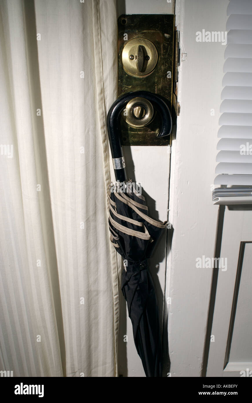 A black umbrella hanging on a brass door nob Stock Photo