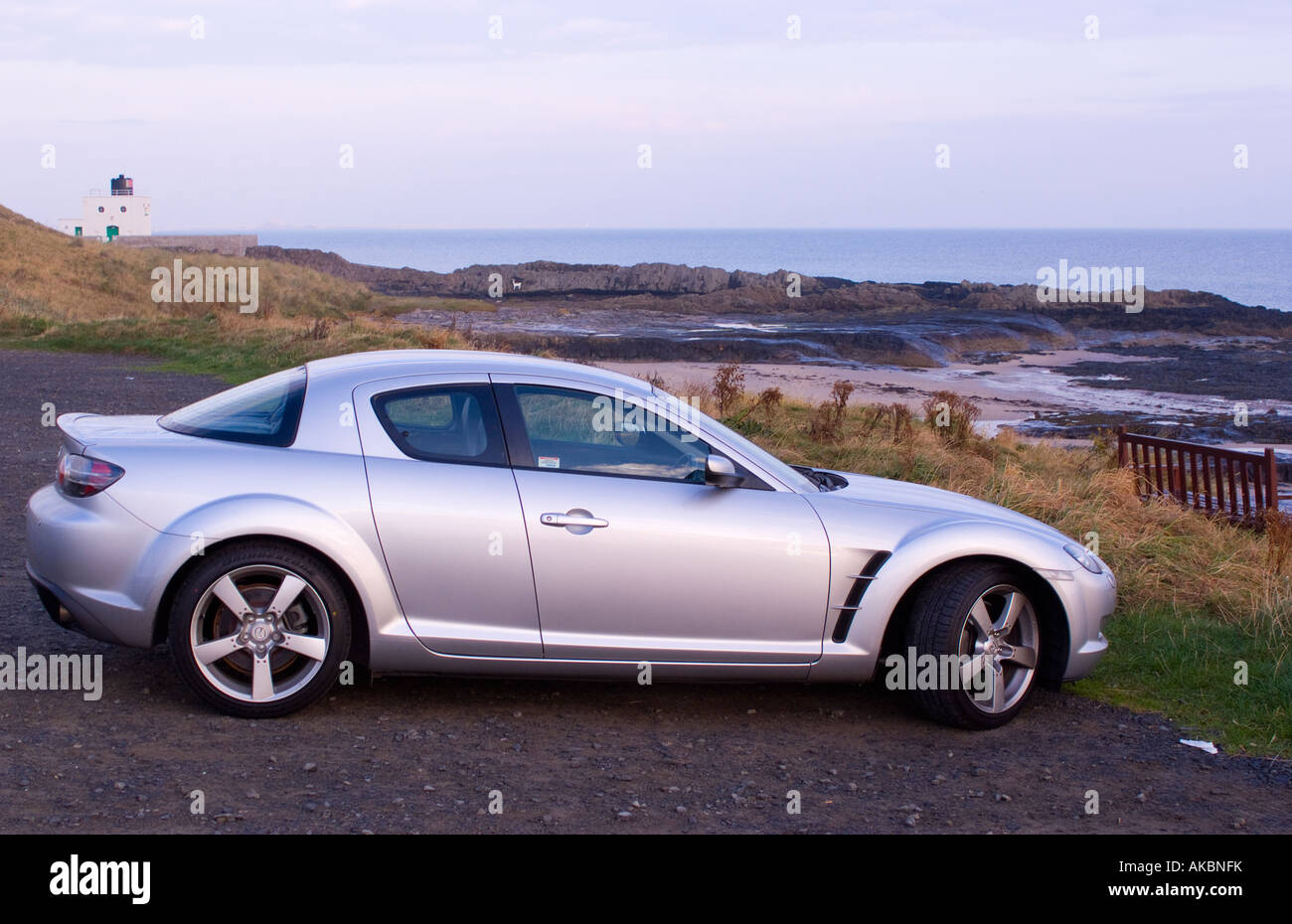 Mazda RX8 Sports Car Parked near Stag Rock Lighthouse in Bamburgh Nothumberland England Stock Photo
