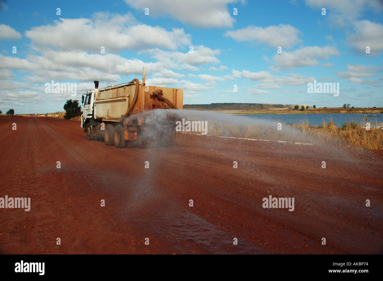 Water truck spraying to suppress dust on coal mining site access road ...