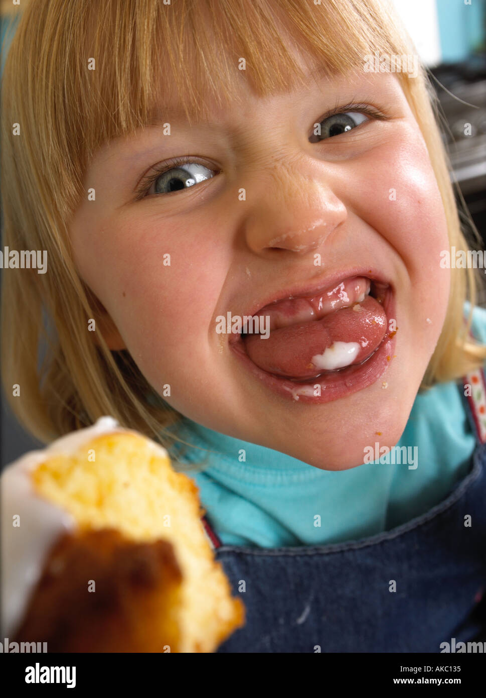 Children cooking cakes in their kitchen at home Girl licking and eating a cake Stock Photo