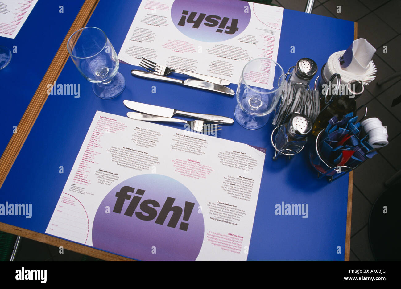 A laid table with menu cutlery glasses and condiments at Fish