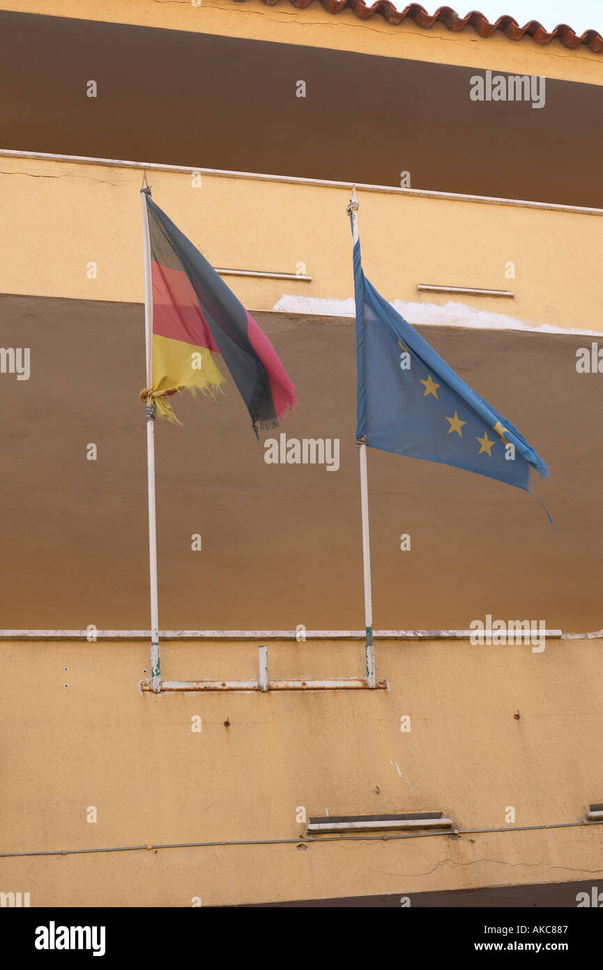 Tatty German and European flags on poles attached to balcony of old building  Stock Photo