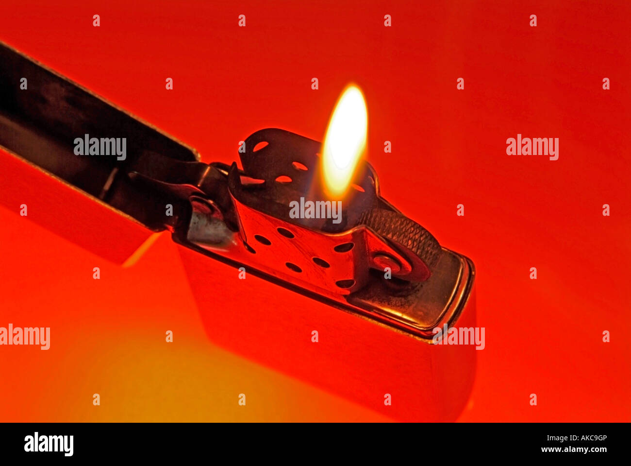 cigarette lighter Zippo with burning flame against red background Stock Photo