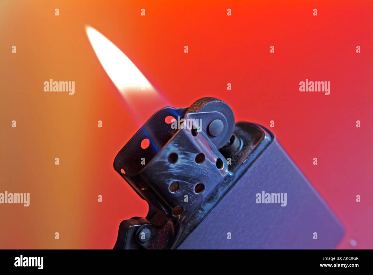 cigarette lighter Zippo with burning flame against red background Stock Photo