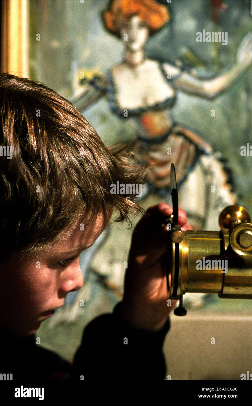 A YOUNG BOY IN AN AUCTION ROOM WITH A VICTORIAN MAGIC LANTERN WITH SLIDES UK Stock Photo