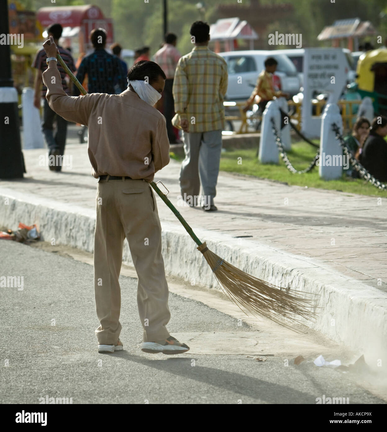 An Indian worker sweeping the road with a traditional broom. He is