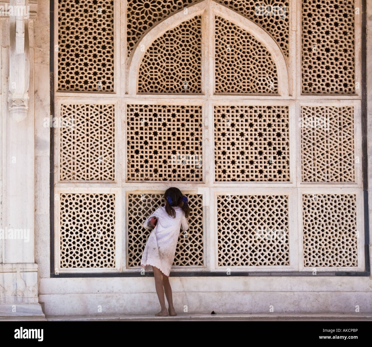 A Young girl peeping though the marble latticework of the tomb of Shaikh Salim Chishti. Fatehpur Sikr, India. Stock Photo