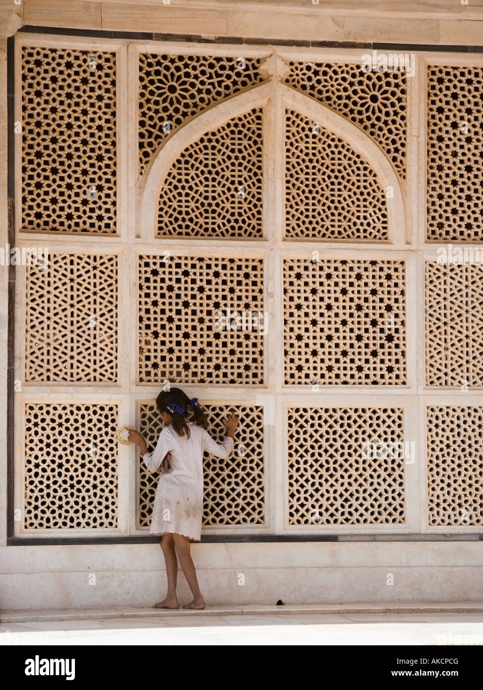 A Young girl peeping though the marble latticework of the tomb of Shaikh Salim Chishti. Fatehpur Sikri, India. Stock Photo