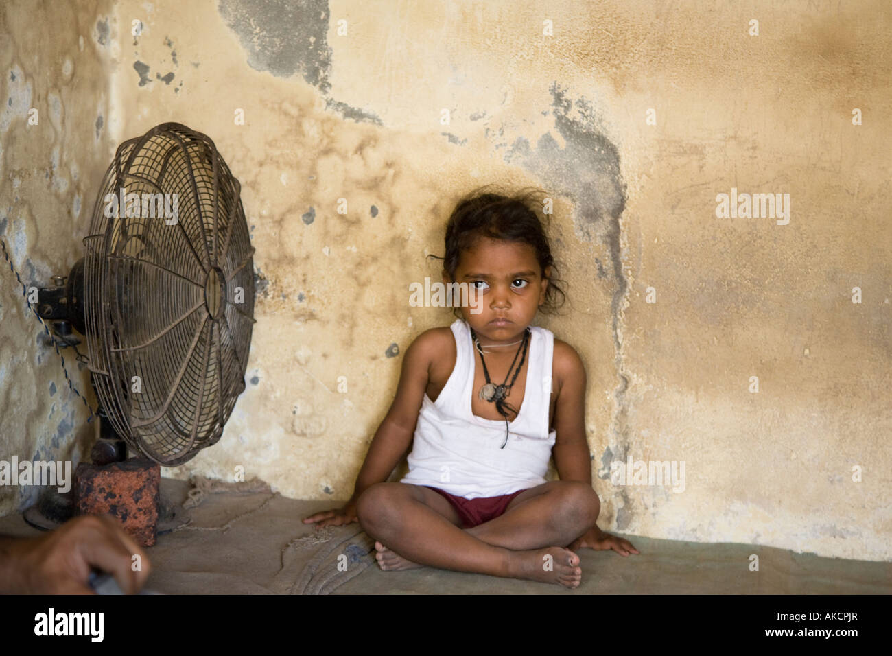 A young Indian child  cooling off next to a fan. Stock Photo