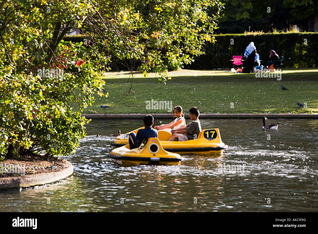 Children playing in pedalo boats in a sunny Regent's Park. A Muslim