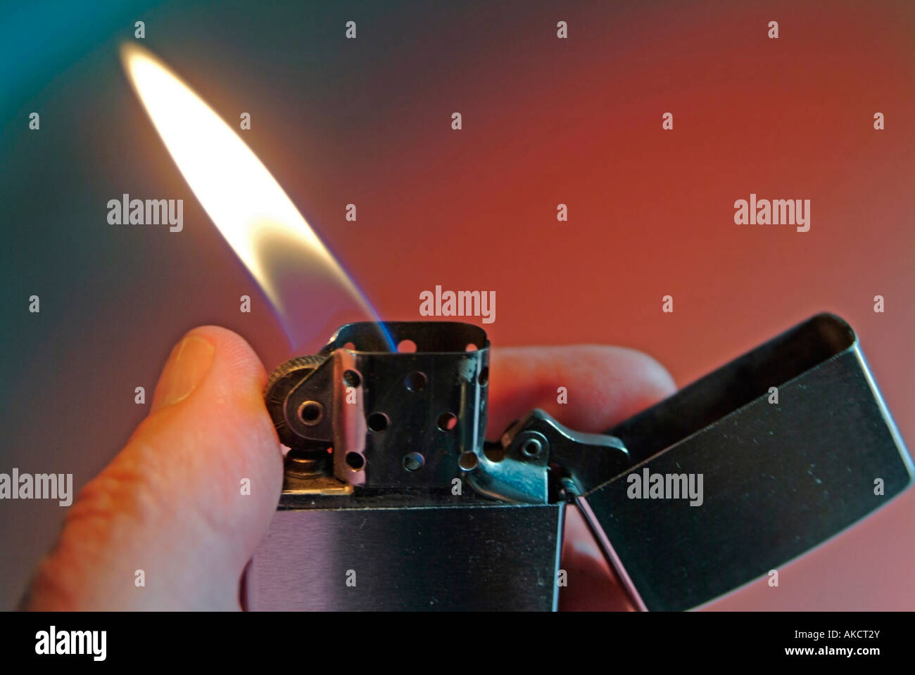 cigarette lighter Zippo with burning flame against red background Stock Photo
