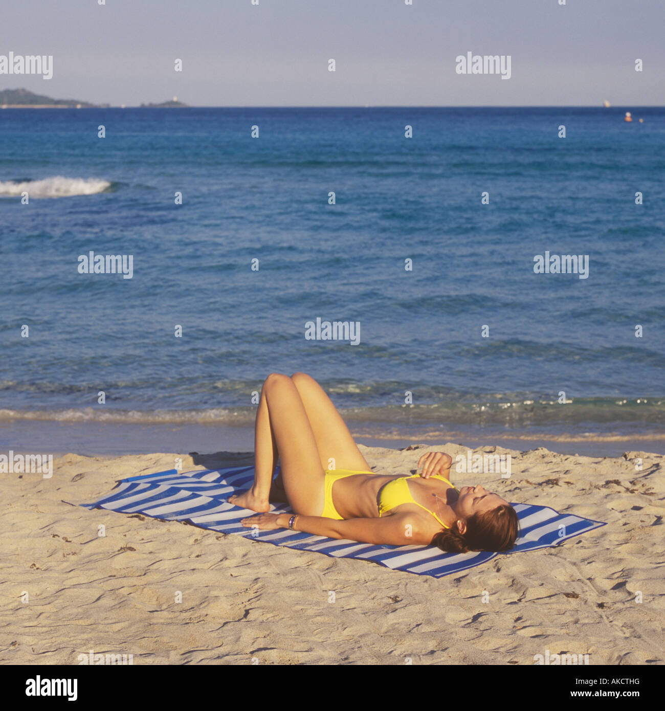Young lady performing pre swim yoga, fitness, exercise and meditation at beach in North East Mallorca. Stock Photo