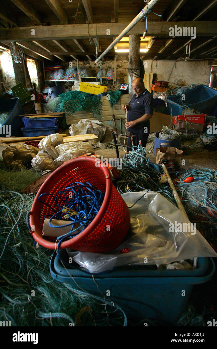 A fisherman fixes nets in the cellars under the artists studios on Porthmeor Beach in St Ives, Cornwall, England, UK Stock Photo