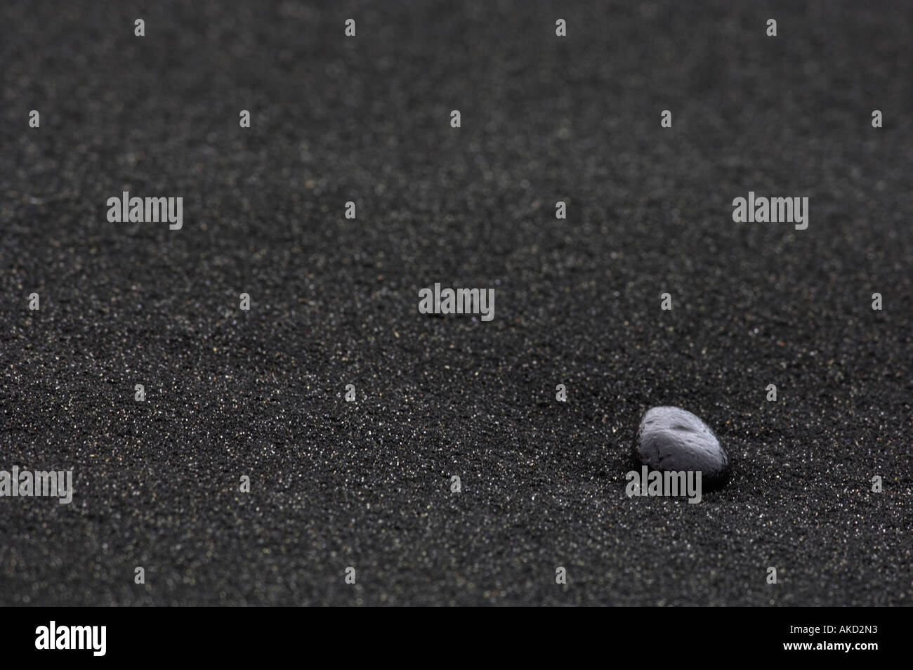 Black stone lying on beach Stock Photo
