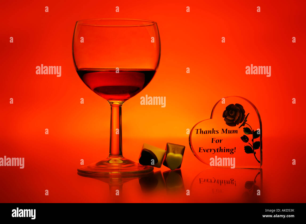 Glass of wine and chocolates on a colorful background with single rose showing mothers day Stock Photo