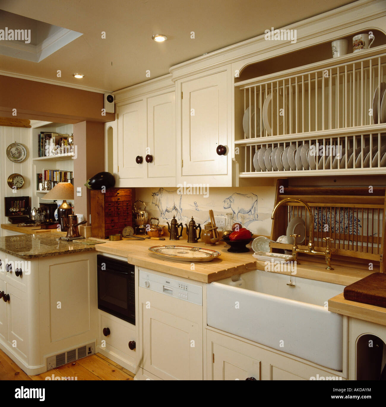 Plate rack above white ceramic sink and integral dishwasher in neutral kitchen Stock Photo