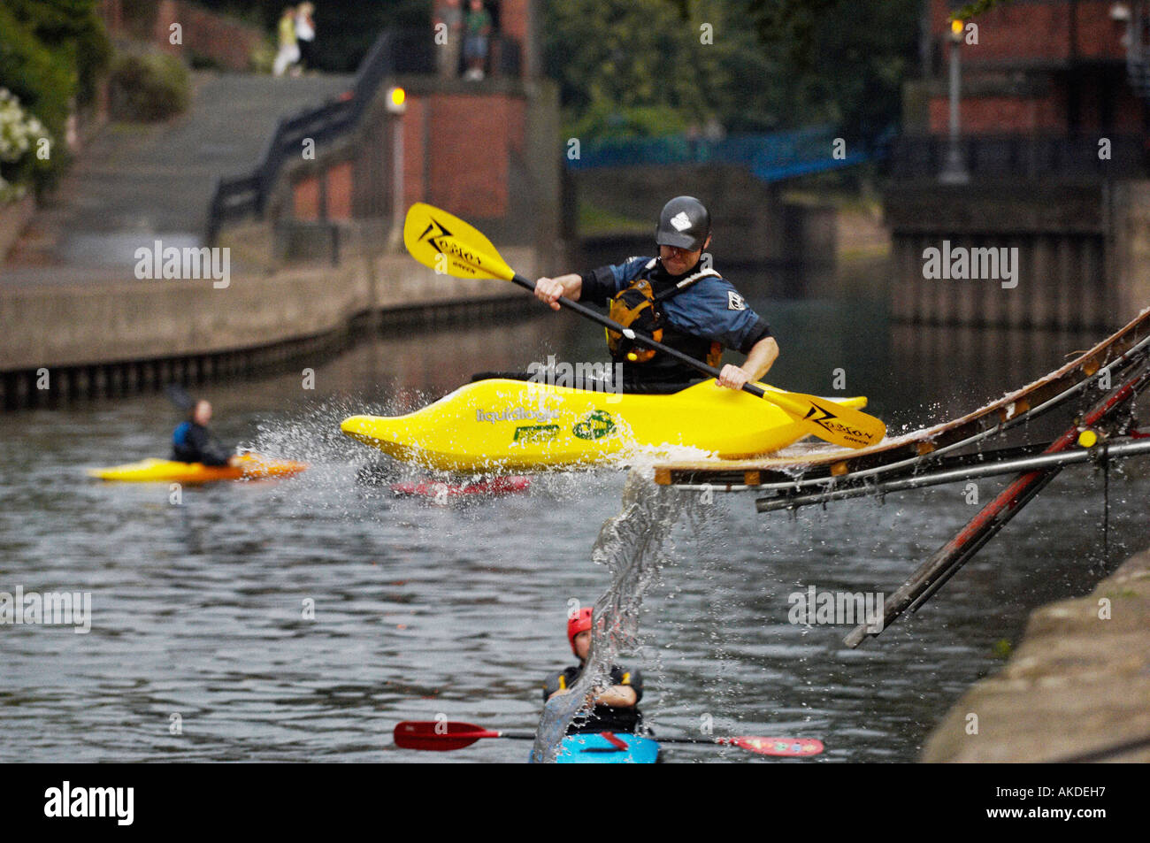 Kayaker in his yellow playboat sliding off a ramp into the river Foss in York. UK Stock Photo