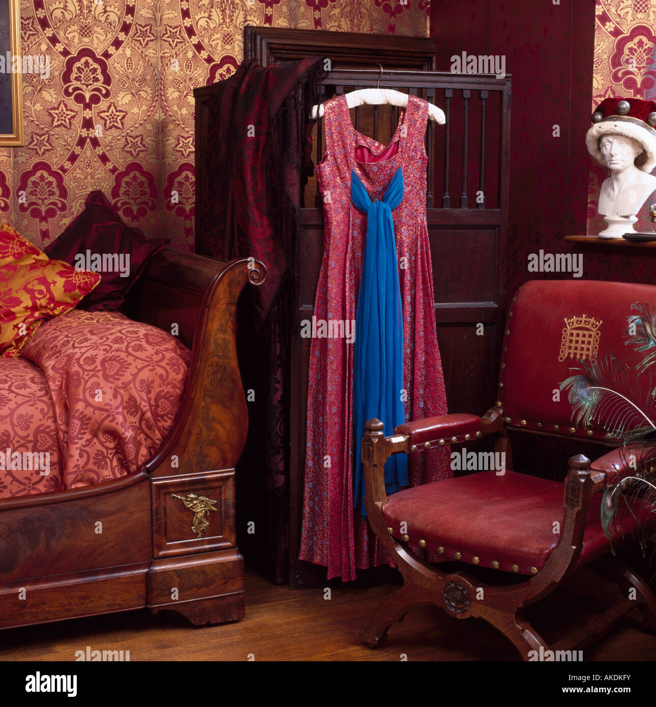 Red dress on mahogany wardrobe in bedroom with red chair and bed linen ...