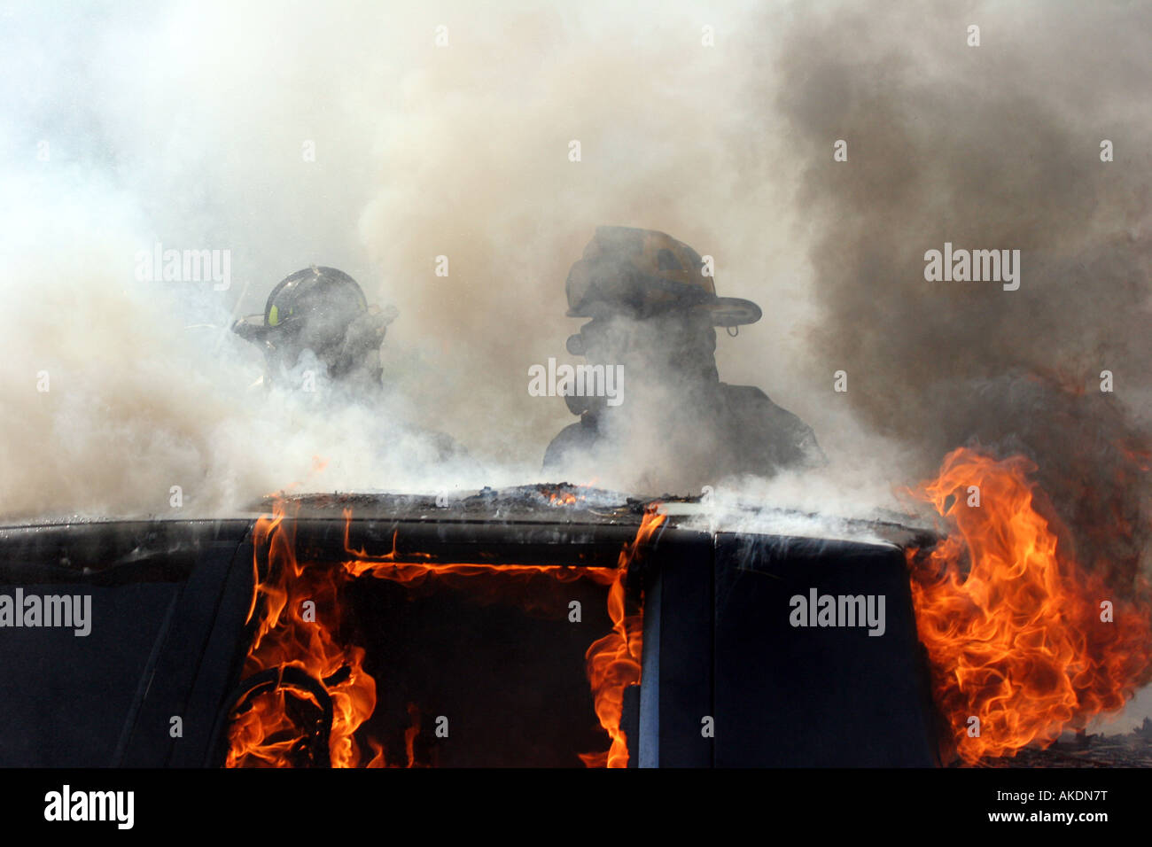 Two firefighters in the middle of smoke and steam during the extinguishment of an auto fire at an emergency scene Stock Photo