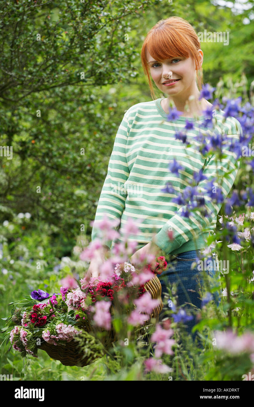 Woman holding basket of flowers in garden, portrait Stock Photo - Alamy