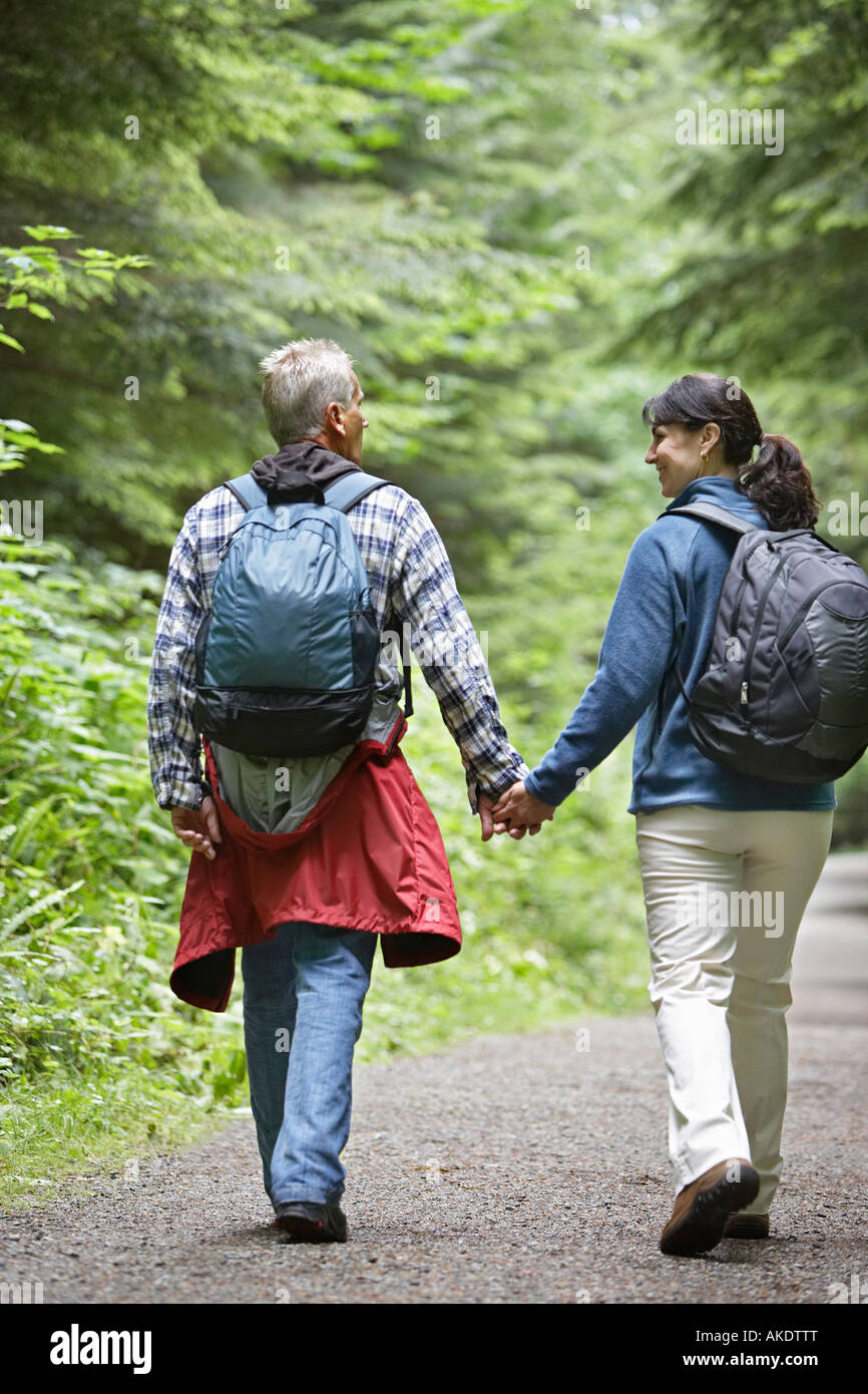 Couple walking along forest road, rear view Stock Photo - Alamy