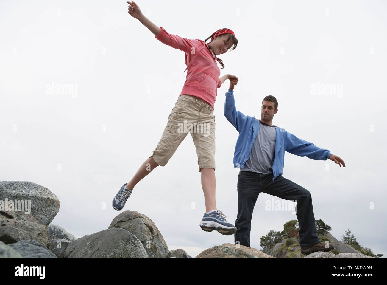 Couple holding hands jumping on rocks Stock Photo - Alamy