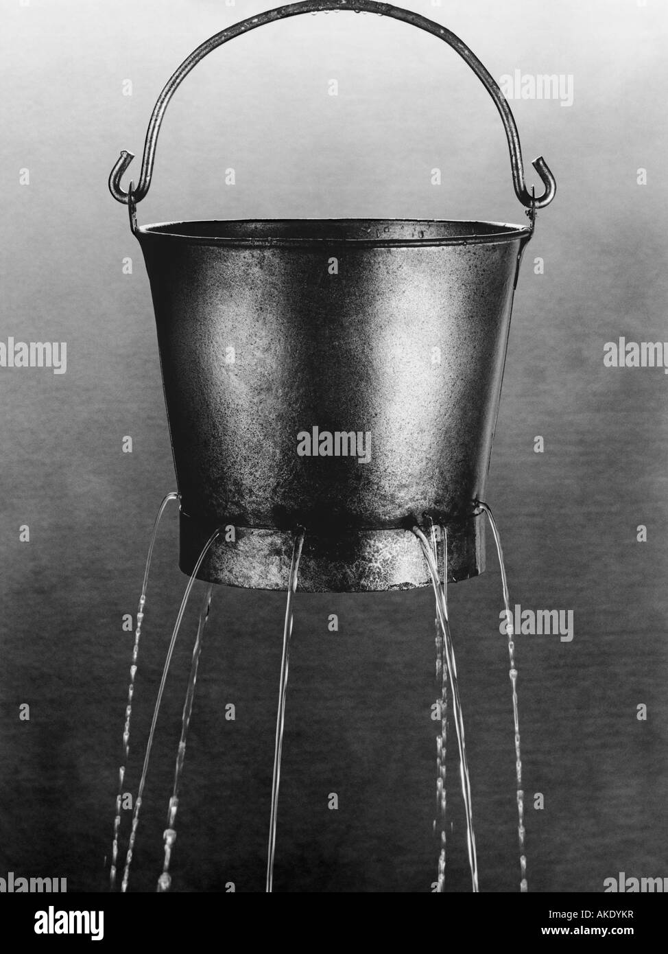 Water poring through holes in bucket, (b&w) Stock Photo