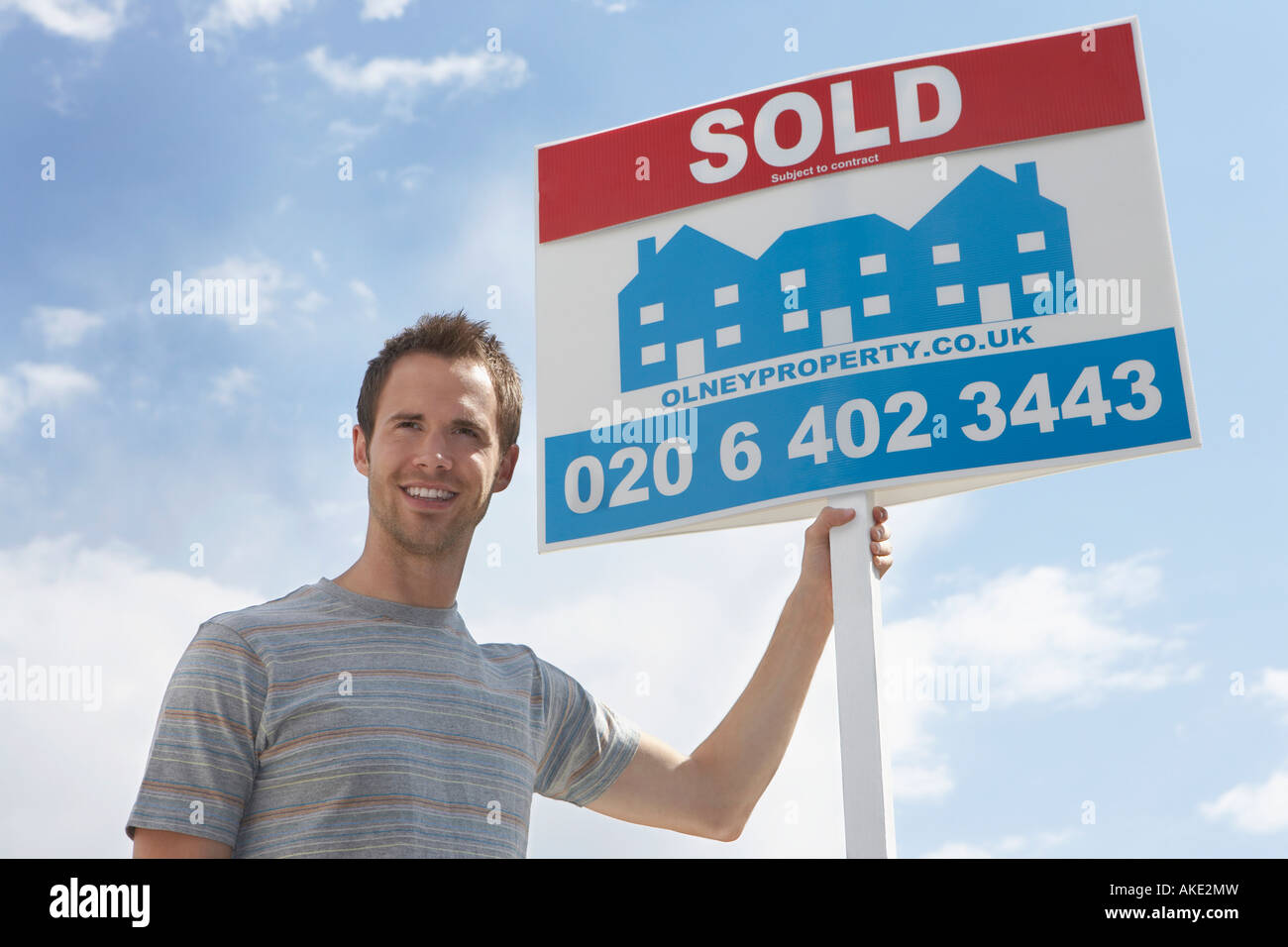 Man holding sold sign, against sky Stock Photo