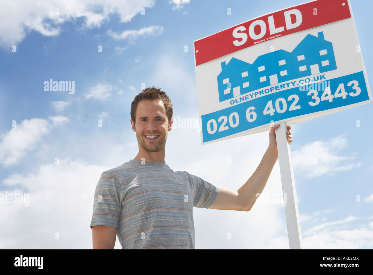 Man holding sold sign, against sky Stock Photo