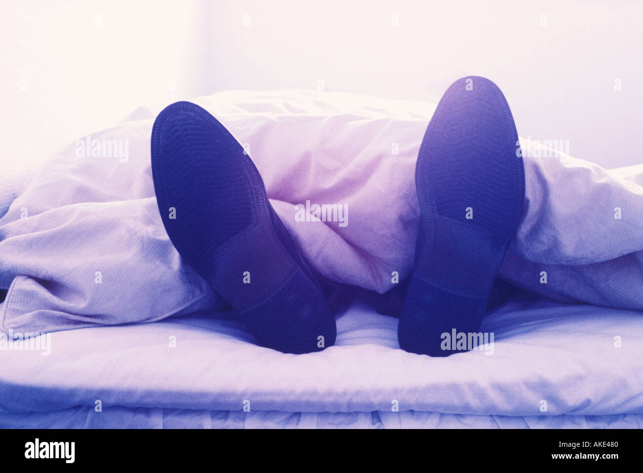 Man in bed with shoes on Stock Photo Alamy