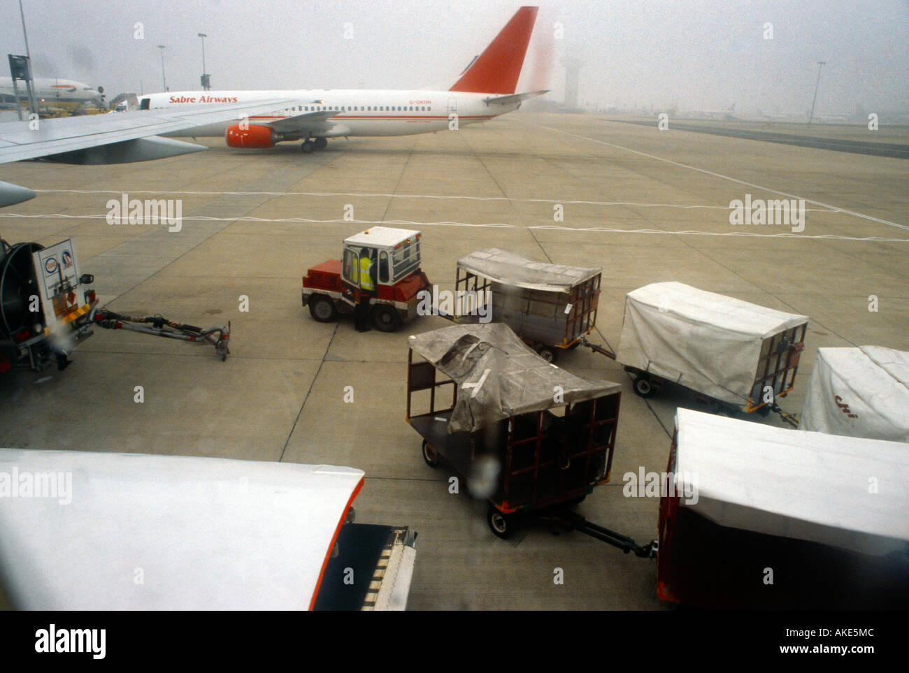 Gatwick Airport Luggage Trailers On Tarmac Going To Plane Stock Photo