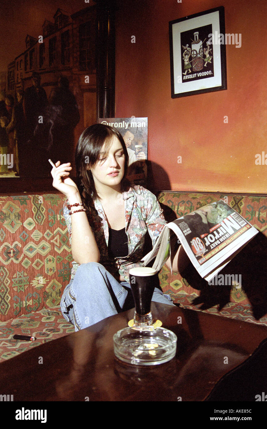 A young woman drinking stout and smoking in the Gateway pub in Cork in
