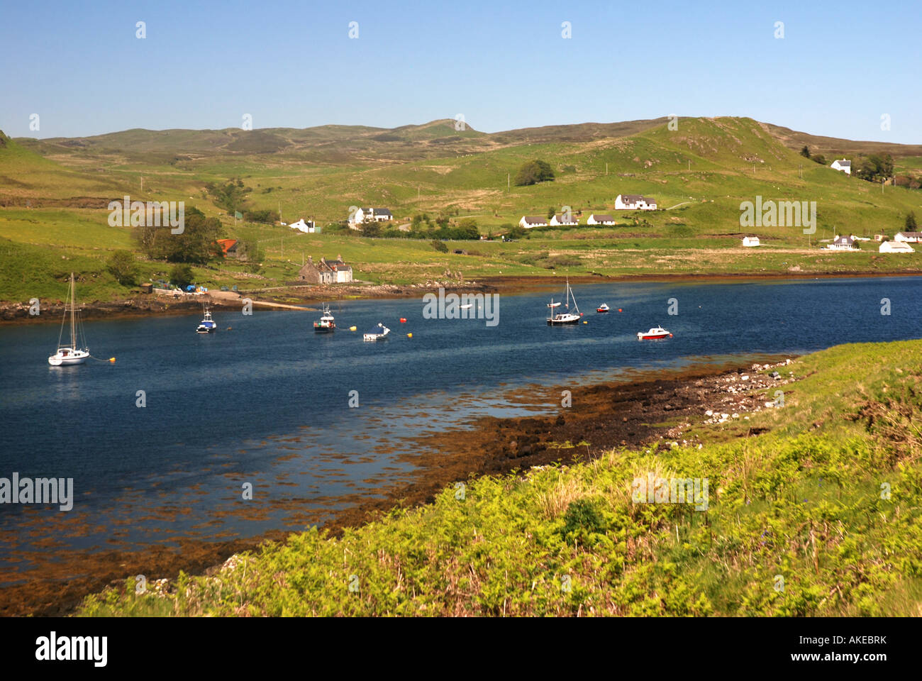 Boats anchored in Loch Dunvegan and farmhouses Island of Skye Inner Hebrides Scotland Stock Photo