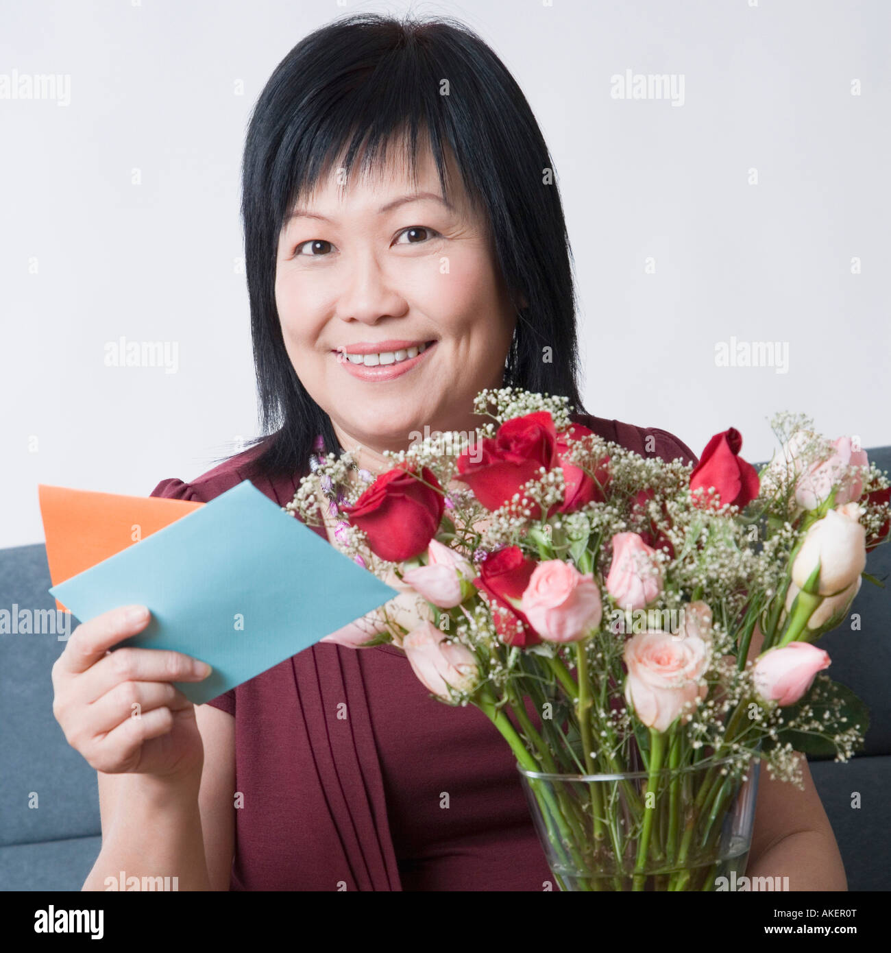 Portrait of a mature woman holding a greeting card and a flower vase ...