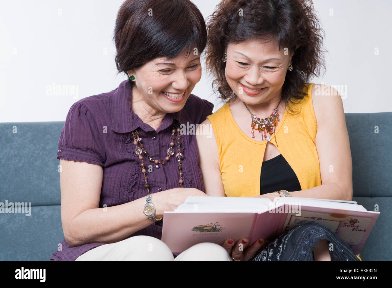 Close-up of two senior women looking at a photo album and smiling Stock Photo