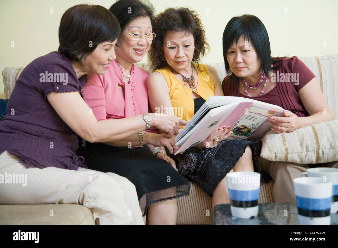 Three senior women and a mature woman sitting on a couch and looking at ...