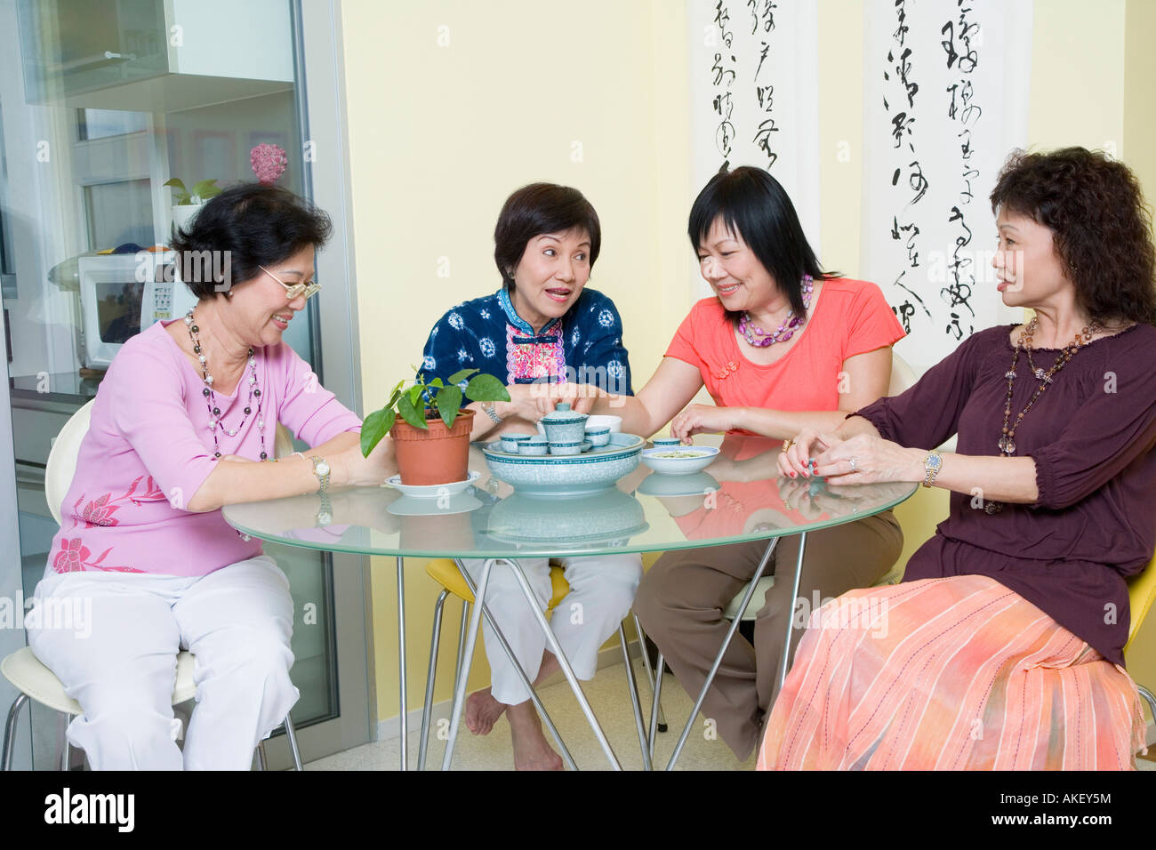 Three senior women and a mature woman sitting at a table Stock Photo ...