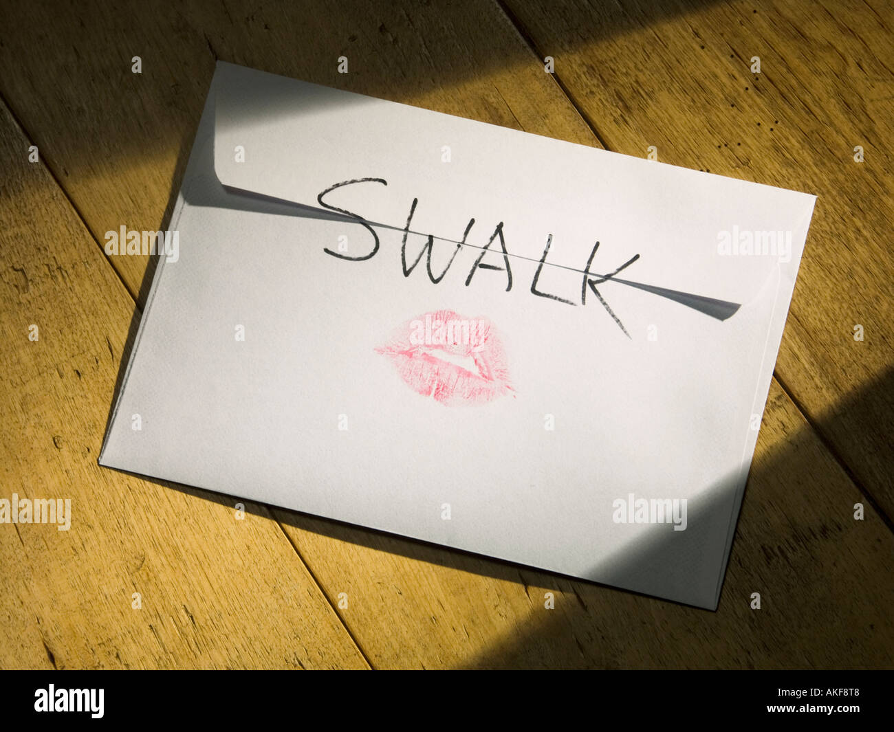 An envelope with SWALK Sealed With A Loving Kiss on the back and a pair of rosy lips Stock Photo