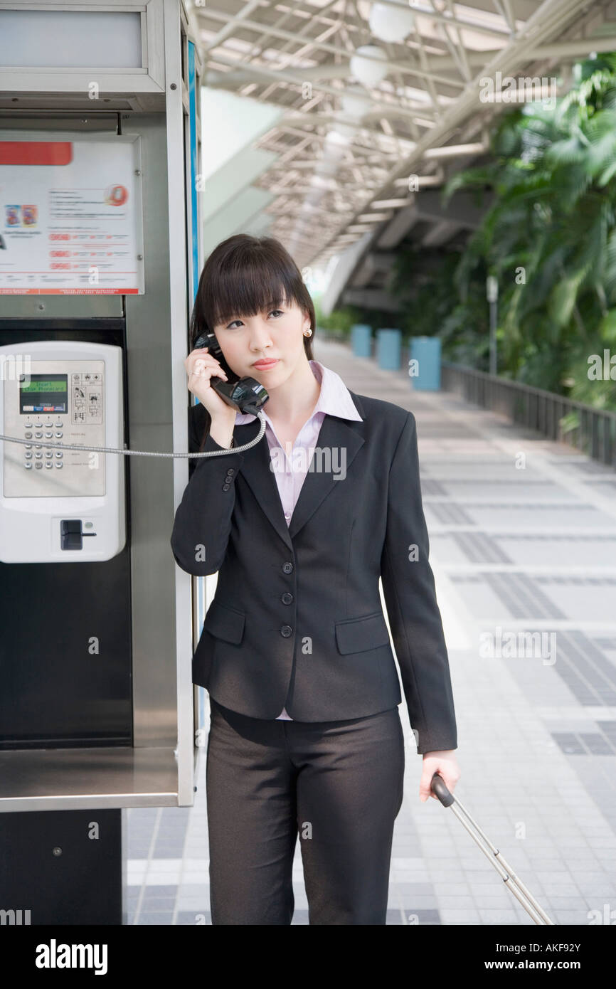 Businesswoman talking on a public phone at an airport Stock Photo