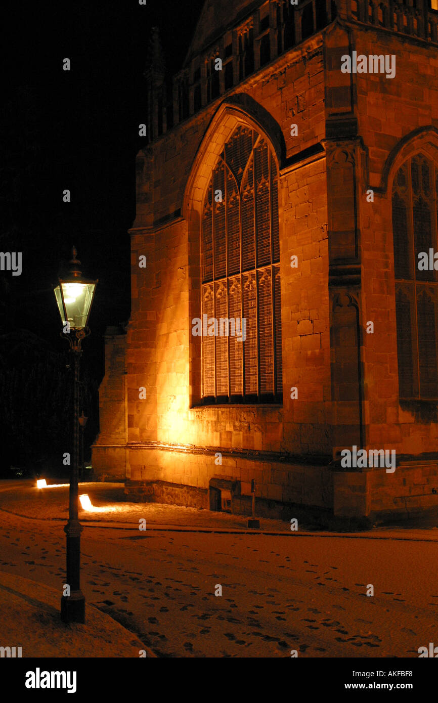 Church window lit up at night with snow on the ground Stock Photo