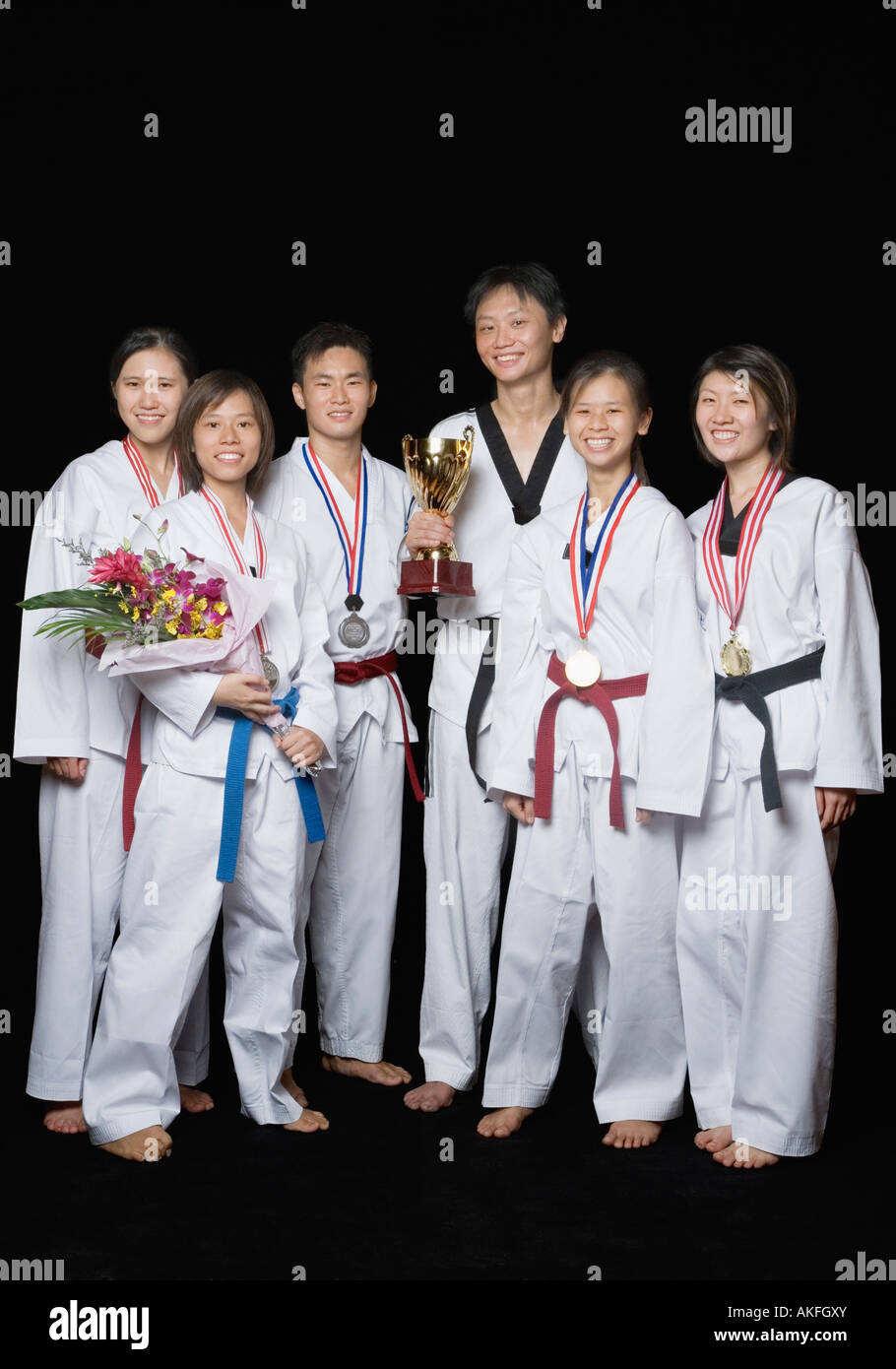 Group of martial arts players standing with their medals and trophies