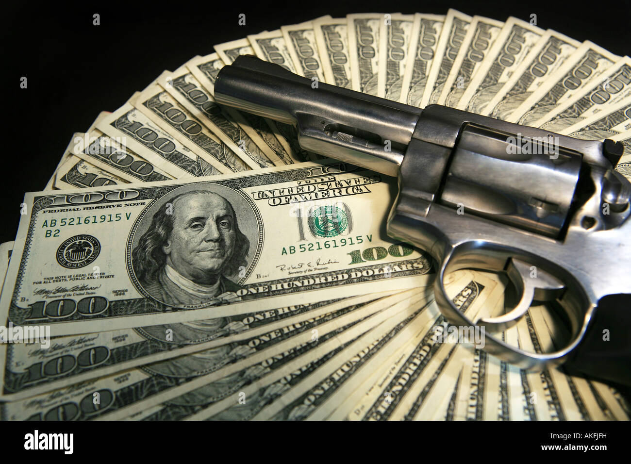 Hand gun on top on one hundred dollar bills isolated on white background Stock Photo