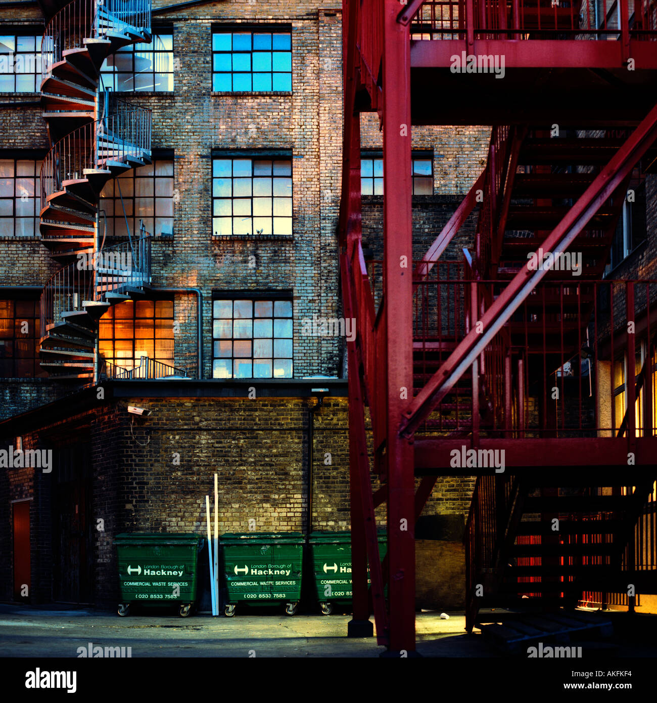 Dusk shot of post-industrial warehouse apartments and fire escapes in Hackney, London, England, 2004; inc. Hackney Council waste bins Stock Photo
