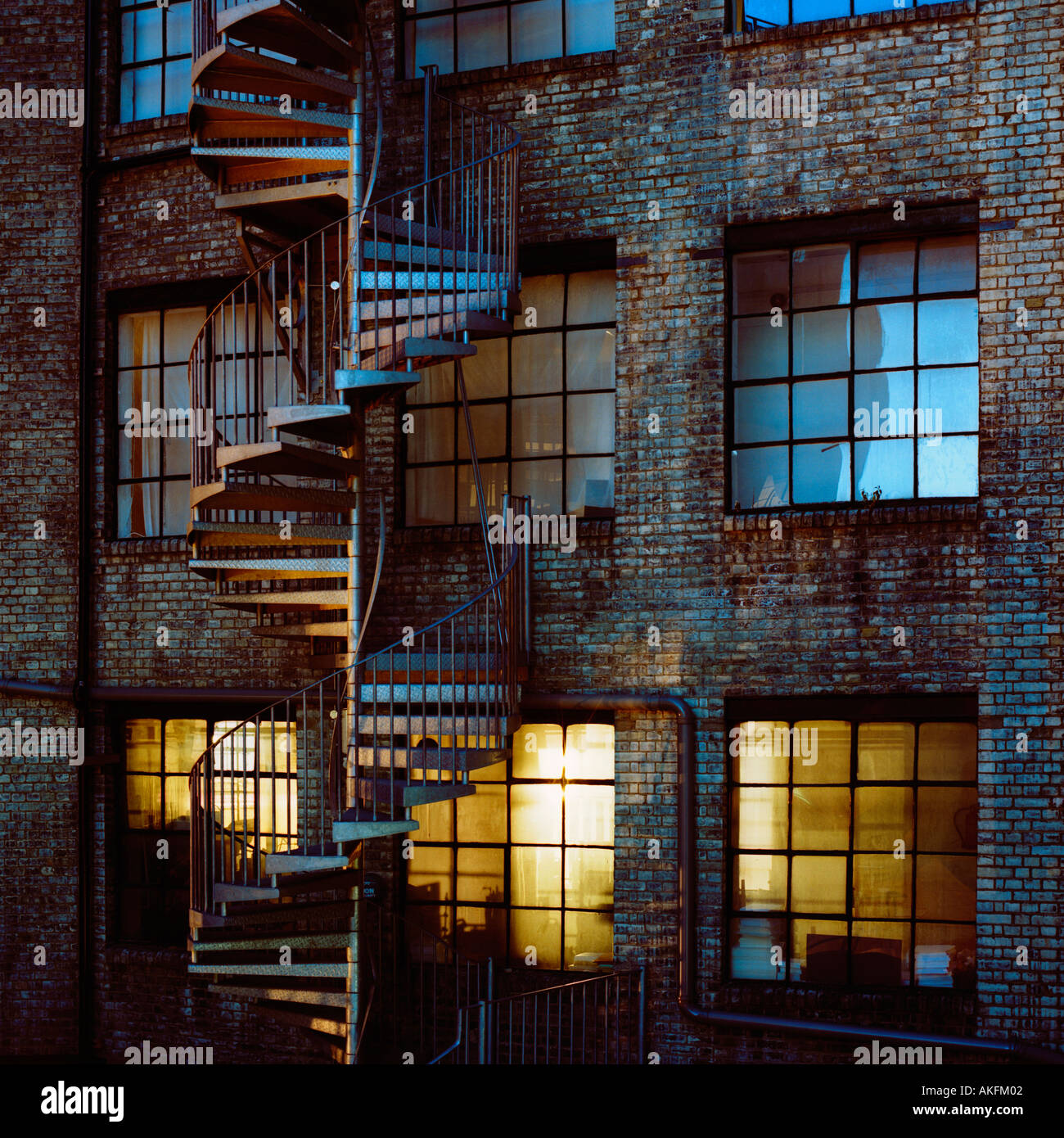 Dusk shot of post-industrial warehouse apartments and a spiral fire escape in Hackney, east London, England Stock Photo
