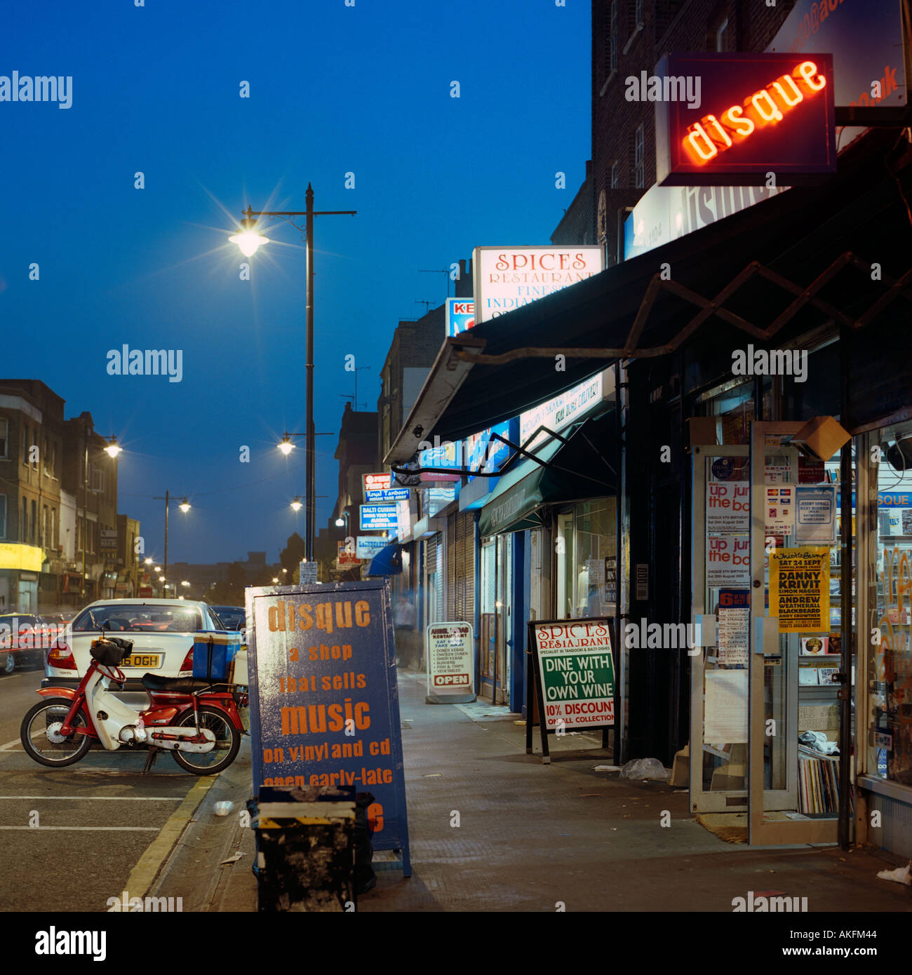 dusk shot of shops and restaurants in Chapel Market north London inc cars neon signs and posters Stock Photo