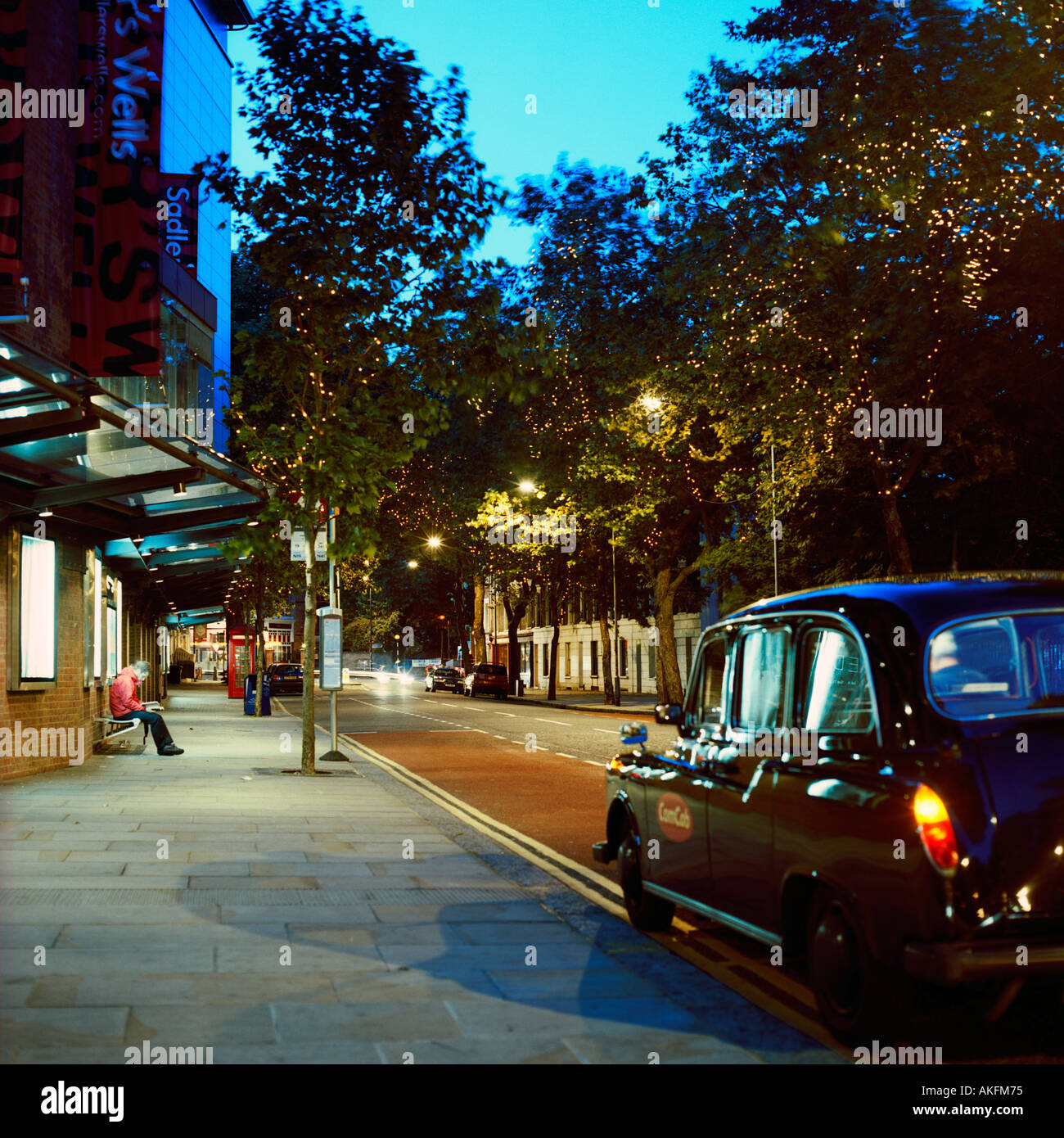 dusk shot of north London street inc contemporary bus stop black London cab from rear Stock Photo
