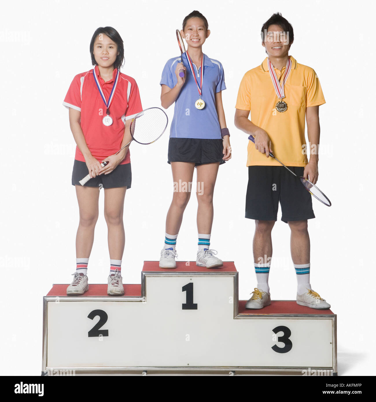 Portrait of two young women and a young man standing on a winners podium and wearing sports medal Stock Photo