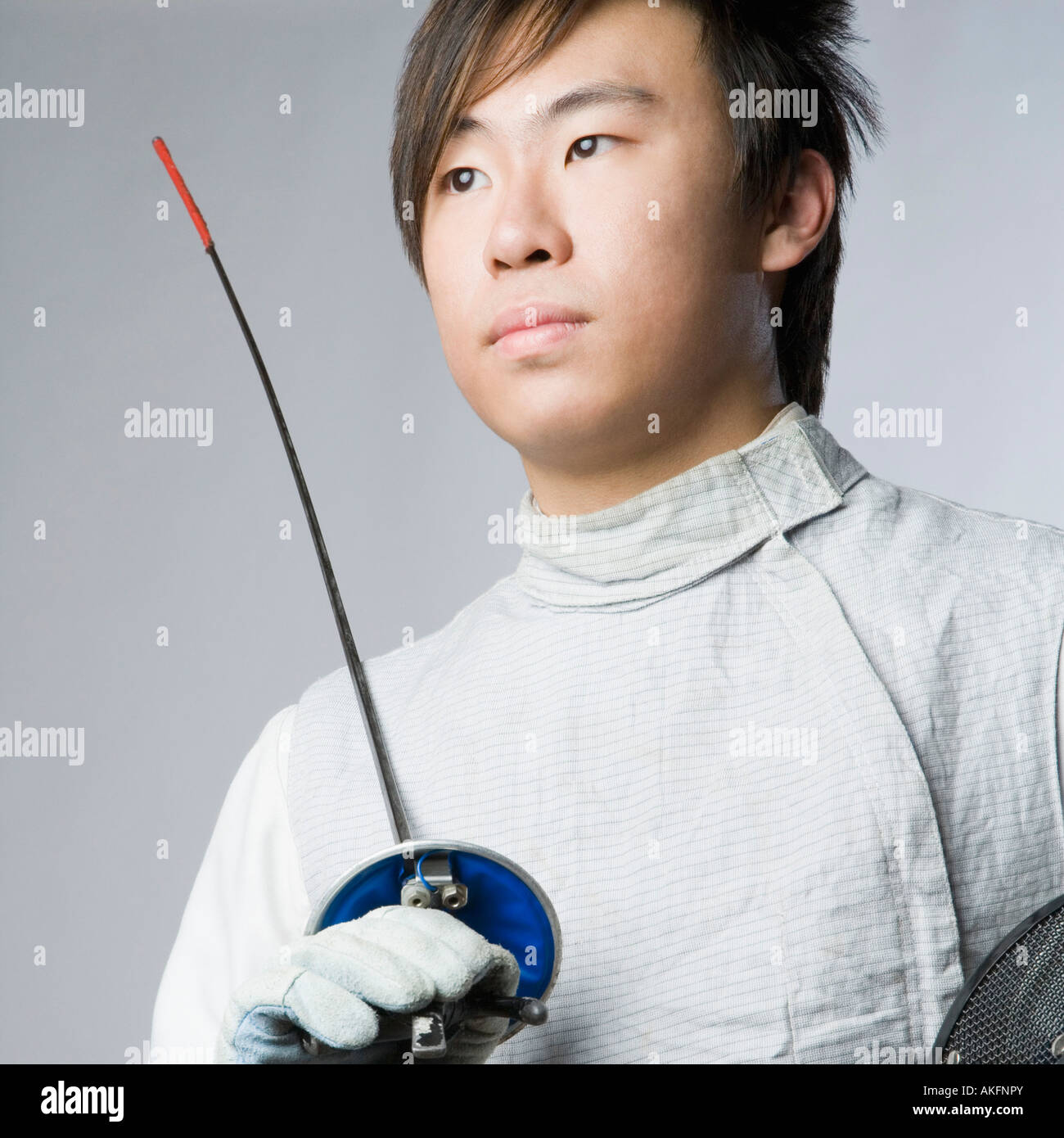 Closeup of a male fencer holding a sword and a fencing mask Stock