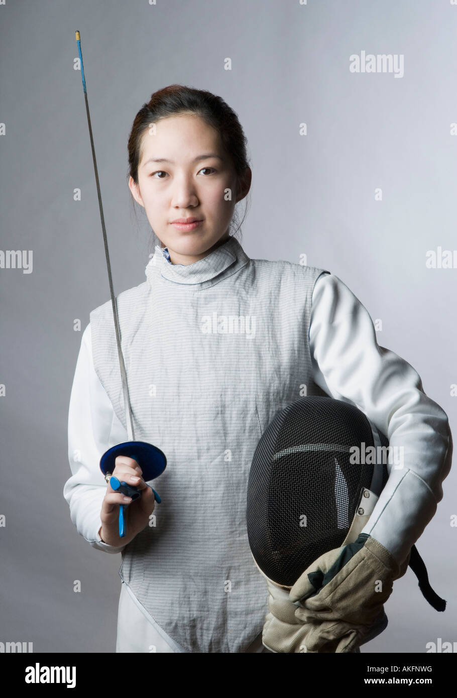 Portrait of a female fencer holding a sword and a fencing mask Stock Photo